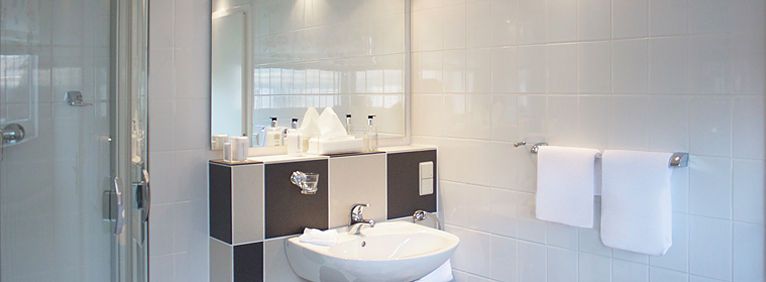 Einblick ins Bad des Einzelzimmer Deluxe mit Waschbecken und Spiegel